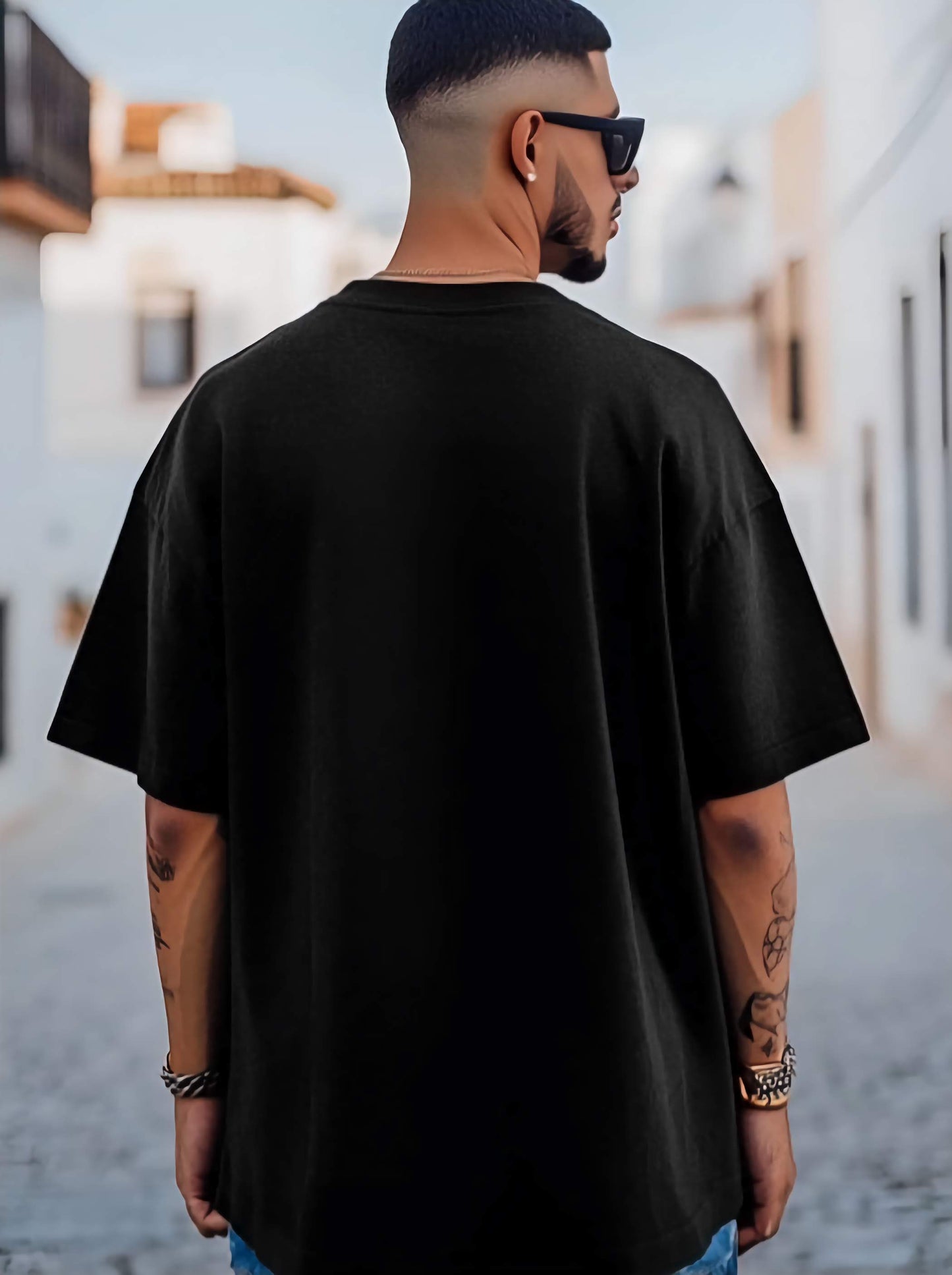 Man wearing a black oversized t-shirt with a blurred background