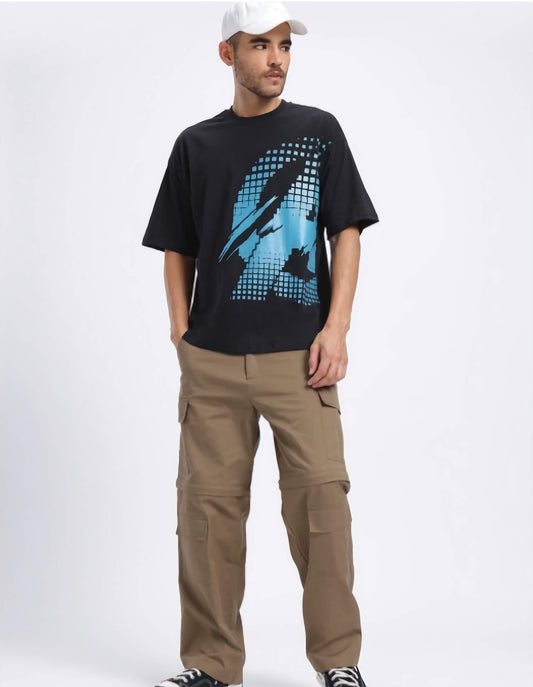 Man wearing a black t-shirt with a marvel captain America graphic design and beige cargo pants on a white background