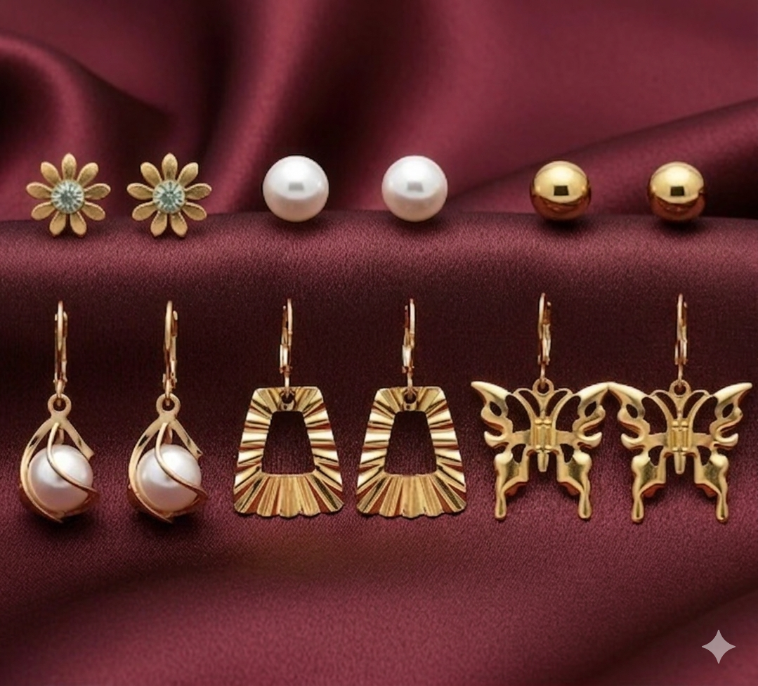 Collection of gold and pearl earrings on a burgundy fabric background