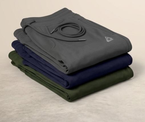 Stack of folded pants in gray, navy, and green on a beige background