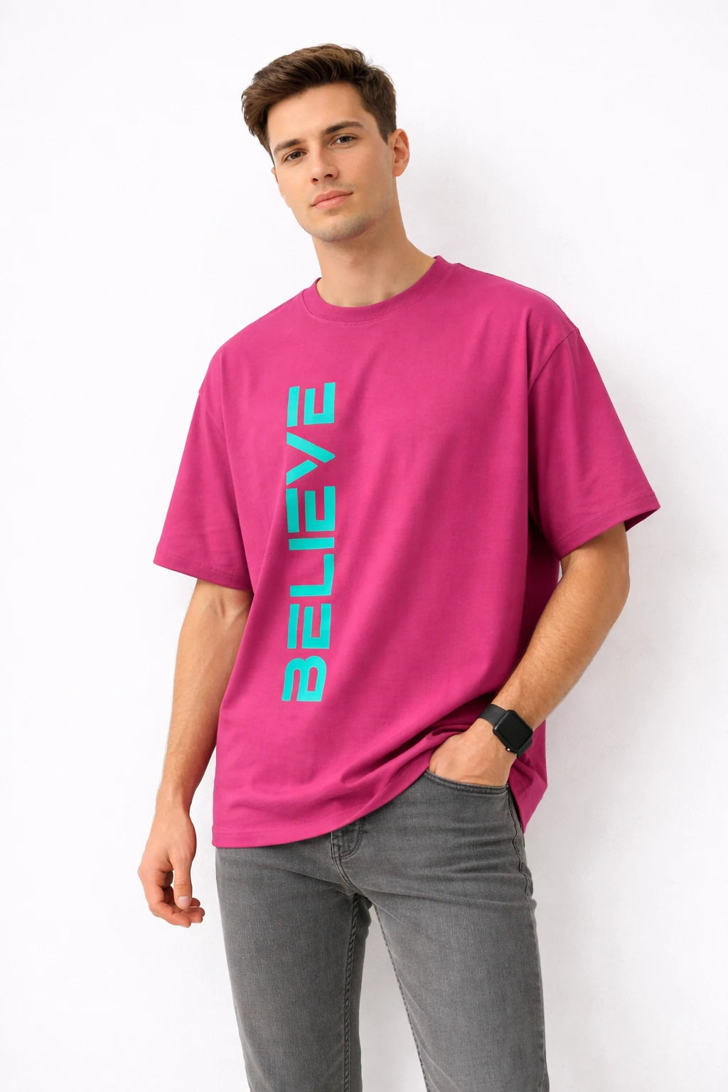 Person wearing a bright pink t-shirt with 'BELIEVE' printed in blue on a white background