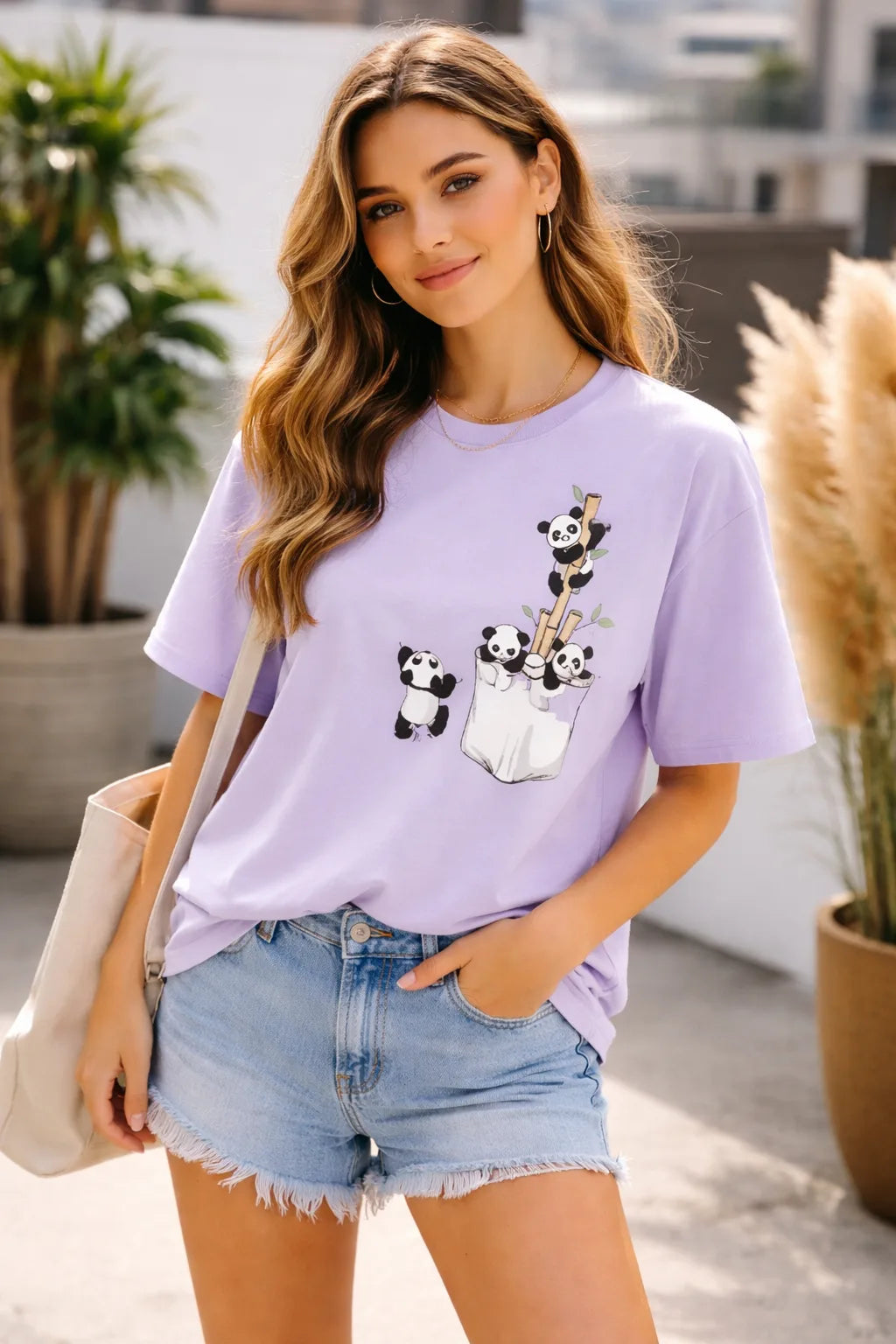 Woman wearing a light purple t-shirt with panda designs outdoors.