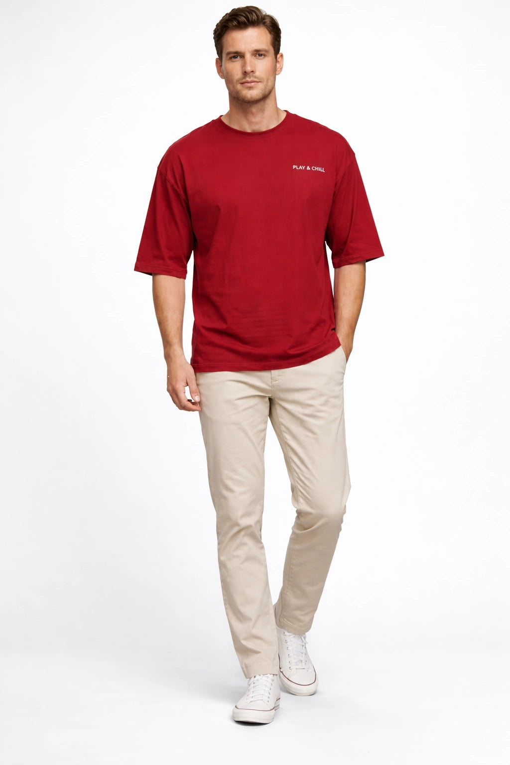 Man wearing a red t-shirt and beige pants on a white background