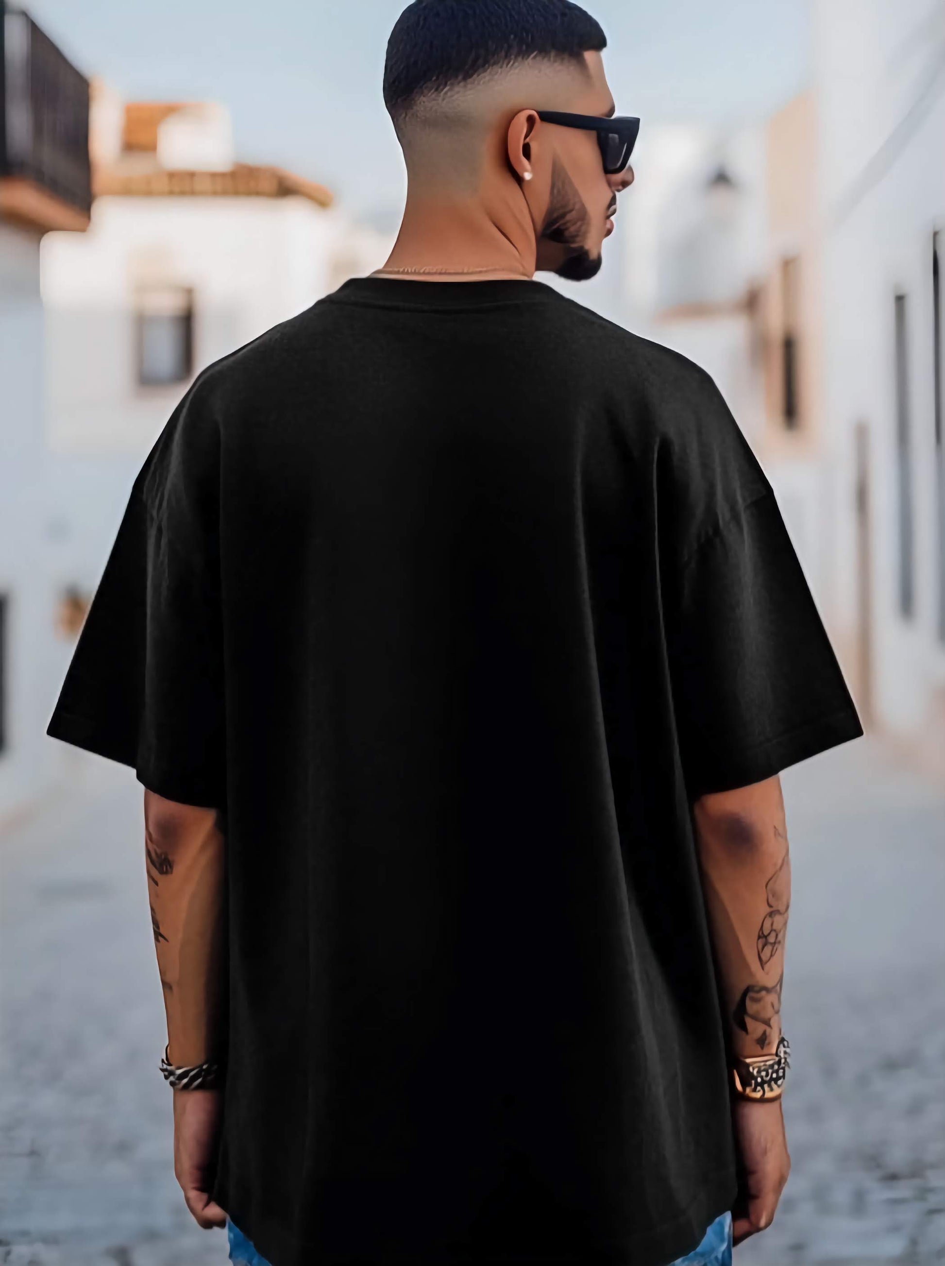 Man wearing a black oversized t-shirt with a blurred background