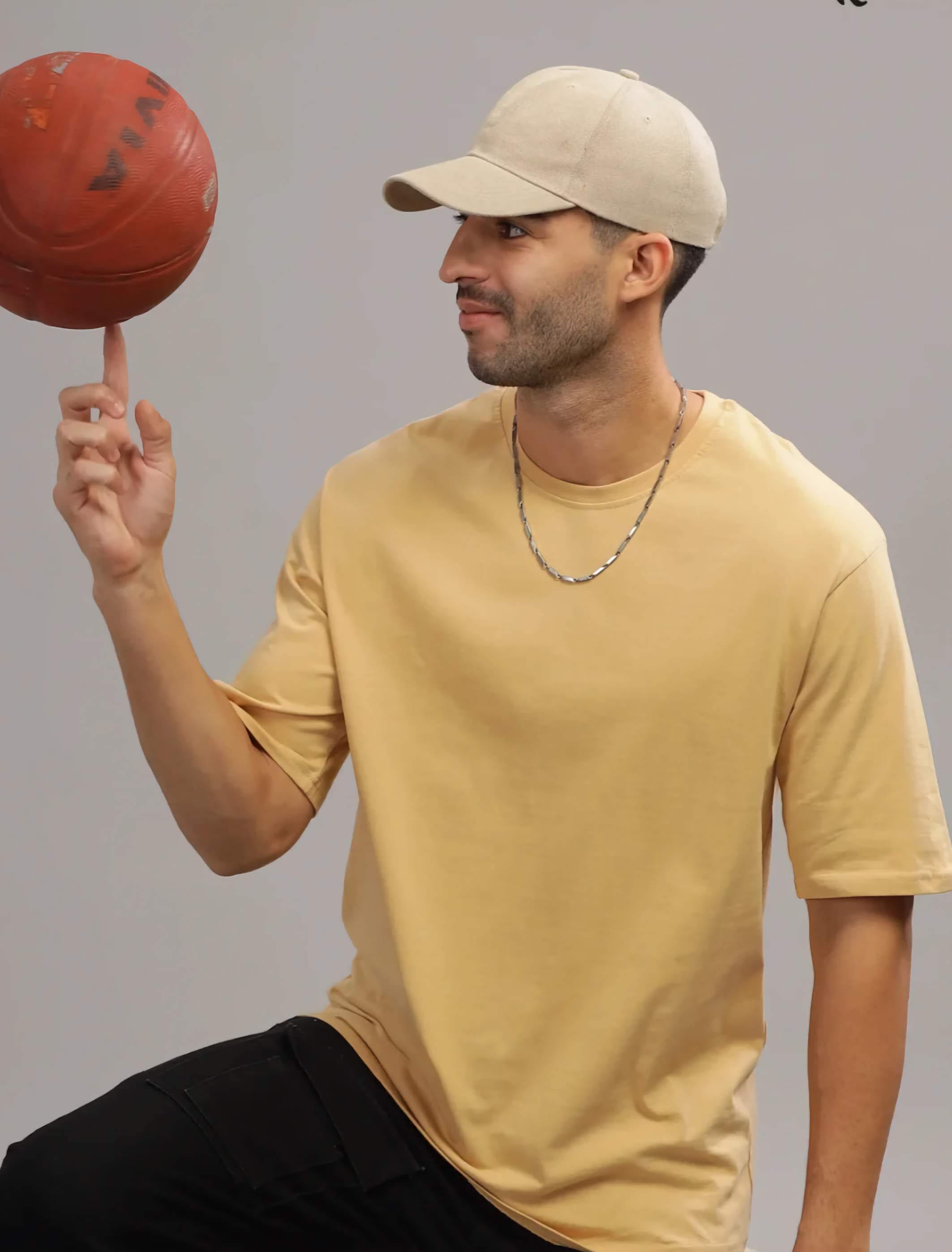 Man balancing a red basketball on his finger against a gray background