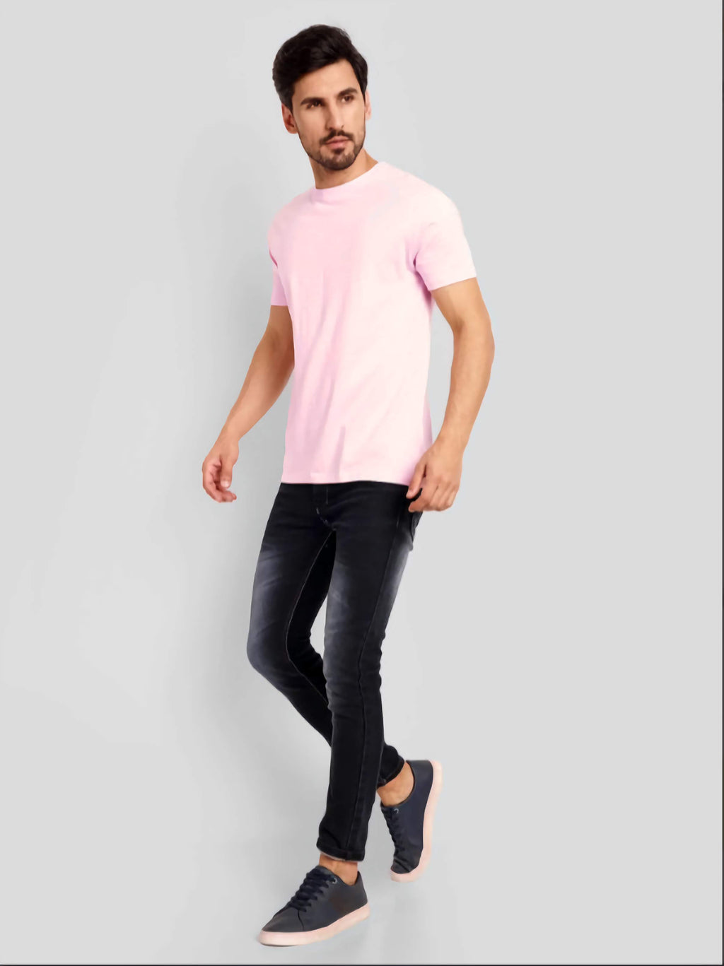 Man wearing a pink t-shirt and black pants on a gray background