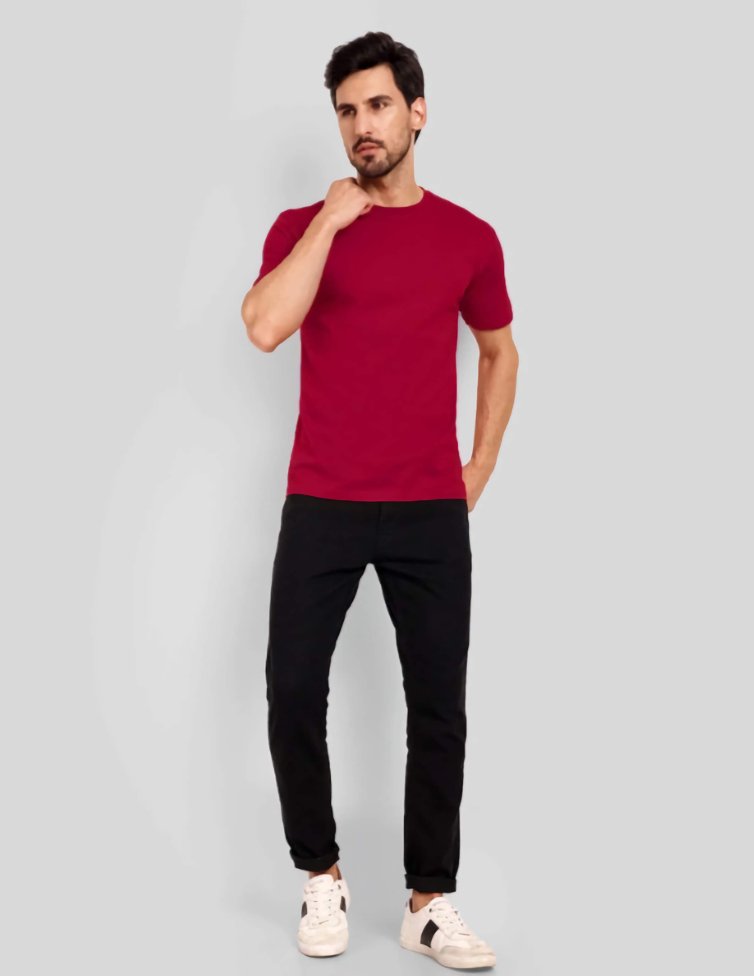 Man wearing a red t-shirt and black pants on a gray background