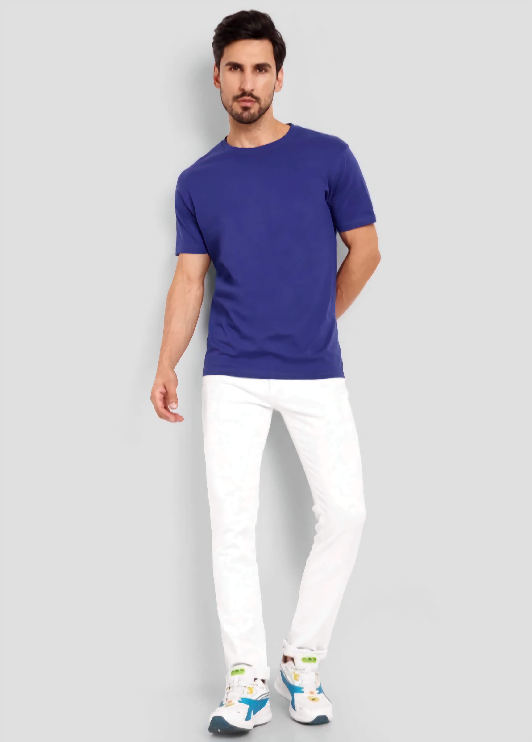 Man wearing a blue t-shirt and white pants on a gray background