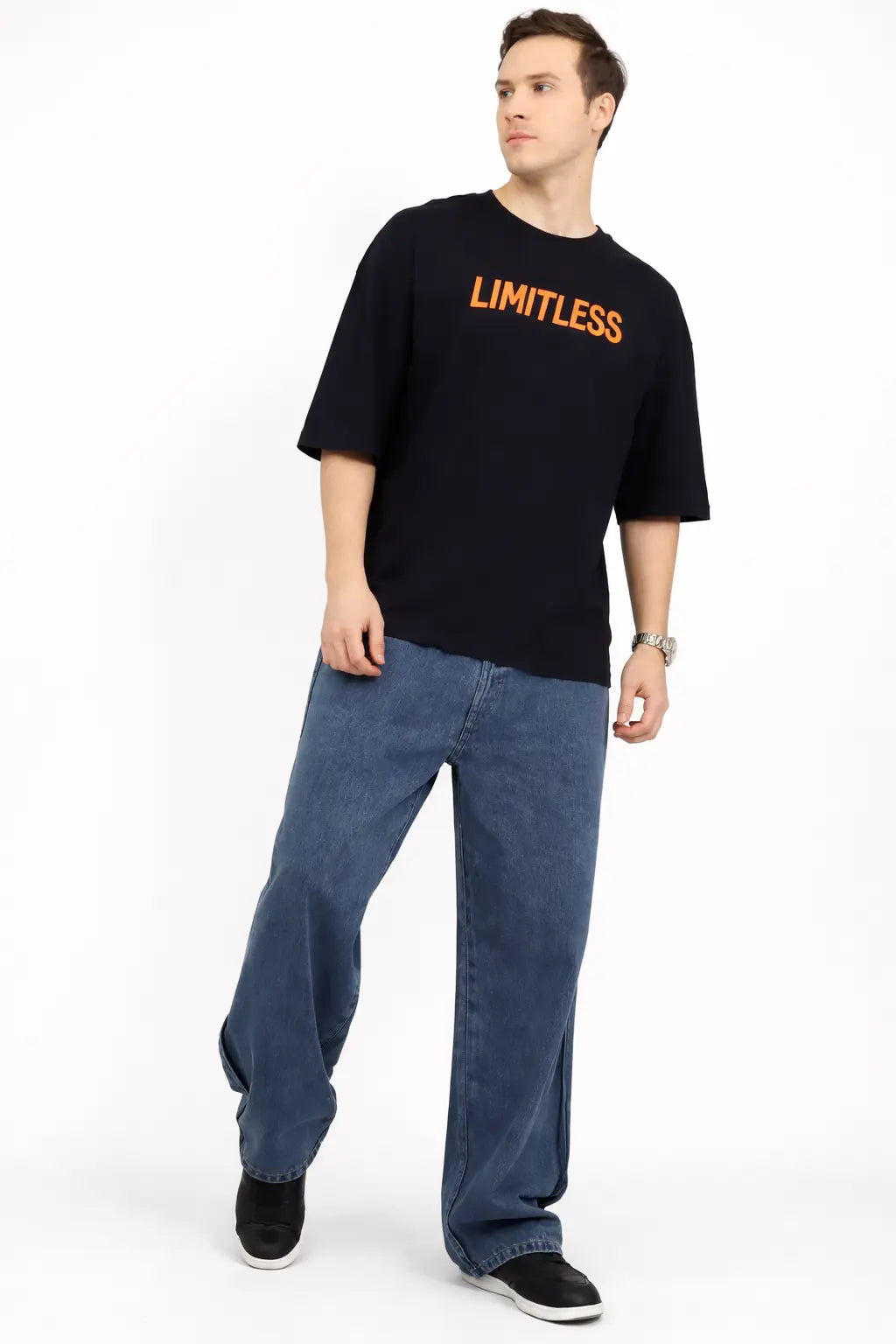 Man wearing a black t-shirt with 'LIMITLESS' text and blue jeans on a white background
