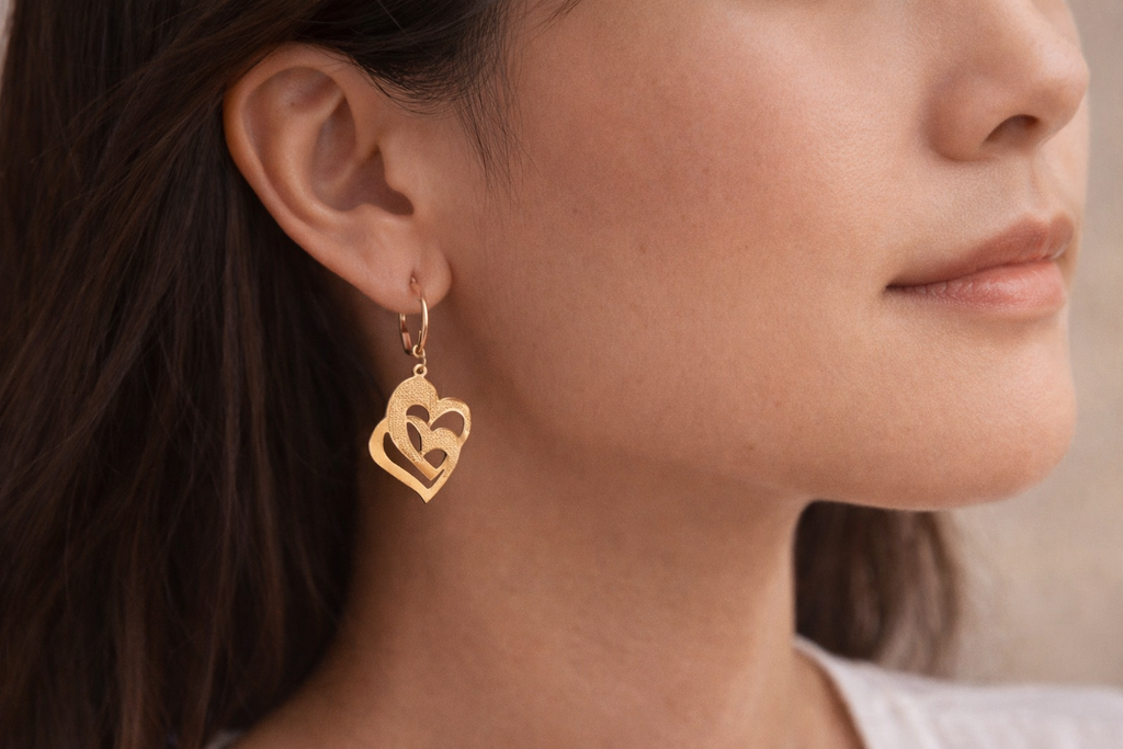 Close-up of a person wearing gold heart-shaped earrings.